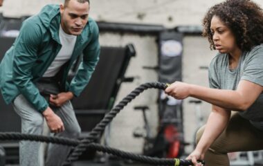 obese woman works out on the ropes with her personal trainer next to her encouraging her