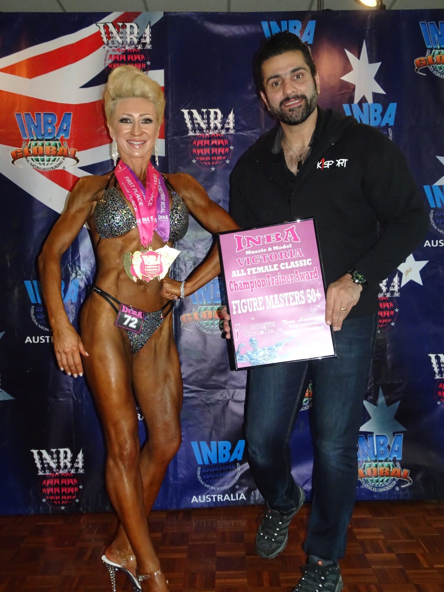 Kaywan holding a certificate with contest preparation bodybuilding client winning award.